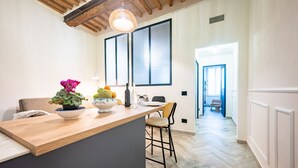 A kitchen with a wooden countertop, a hanging light fixture, and a view into the dining area.