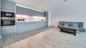 Une cuisine moderne dotée d’appareils électroménagers intégrés, de meubles de rangement gris et d’un plancher en bois.
