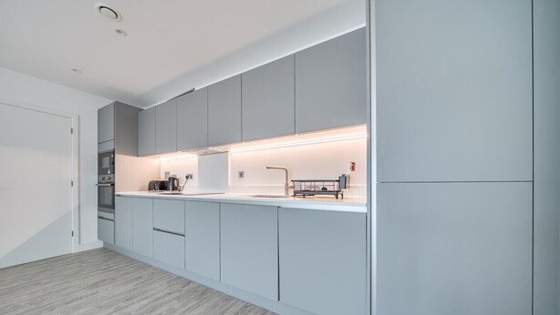 Une cuisine moderne avec des meubles de couleur grise, un plan de travail blanc et des appareils électroménagers intégrés.