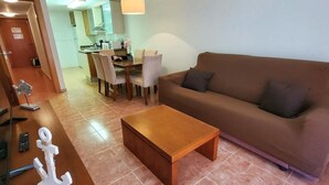 A living room with a brown sofa, a wooden coffee table, and a dining area with chairs and a table. - Seaside apartment in Vera with terrace (vera)