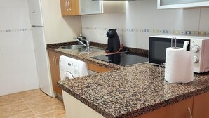 A kitchen with granite countertops, a microwave, a kettle, and a dishwashing machine. - Seaside apartment in Vera with terrace (vera)