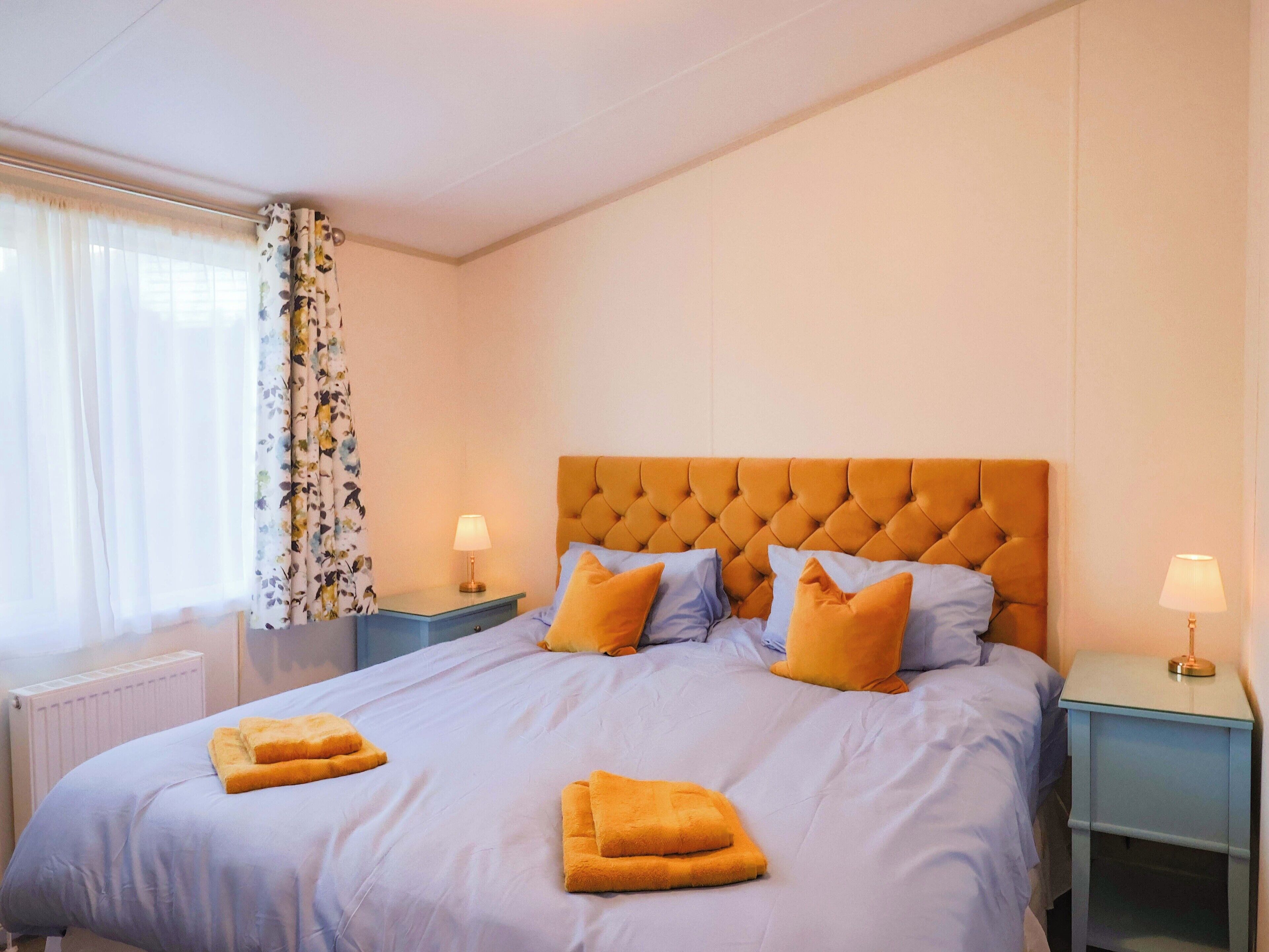 Habitación de hotel con una cama grande, dos mesitas de noche y una ventana con cortinas.