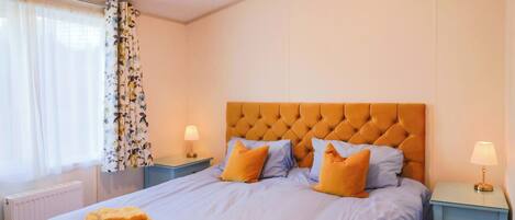 Habitación de hotel con una cama grande, dos mesitas de noche y una ventana con cortinas.