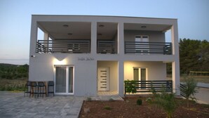 Un edificio de dos pisos con un balcón, una puerta y un cartel que dice 'villa Jana'.