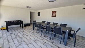 Una habitación con una mesa de comedor, sillas, una mesa de fútbol de mesa y un coche de juguete pequeño.