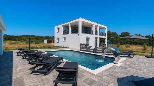 Una casa moderna de dos pisos con piscina, muebles de exterior y vista al campo.