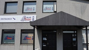 Ein Gebäude mit zahlreichen Fenstern, in denen das Logo 'Blue Viking' zu sehen ist, einem Eingangsschild und einem überdachten Eingangsbereich.