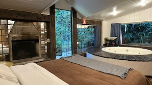Une pièce avec une cheminée, une grande fenêtre, une baignoire et un lit.