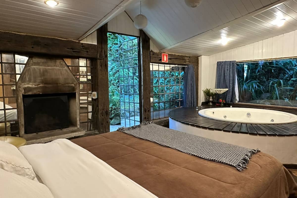 Een kamer met een open haard, een groot raam, een badkuip en een bed.