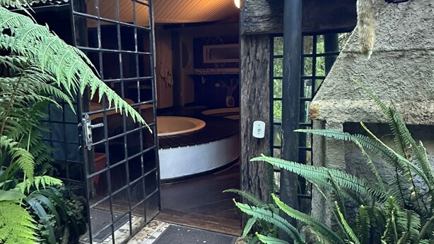 Un bâtiment rustique en bois, doté d’un toit de verre, d’un escalier en bois et d’une porte donnant sur l’intérieur.