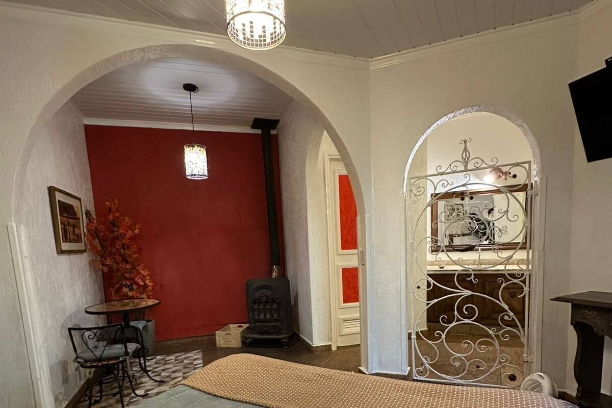 Een slaapkamer met een bed, een kroonluchter, een open haard en een klein tafeltje met stoelen.
