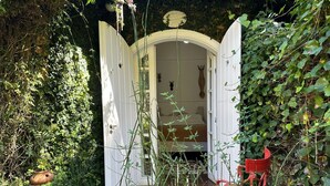 Une porte blanche entrouverte donnant sur une pièce où se trouvent un lit et une sculpture fixée au mur.