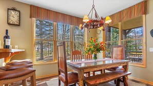 A dining area with a wooden table, chairs, and a bench. There is a chandelier above the table, and a clock on the wall. - Ski •Soak •Savor Haven – Private Hot Tub, Private Garage - Walk to Lifts & Town (Breckenridge)
