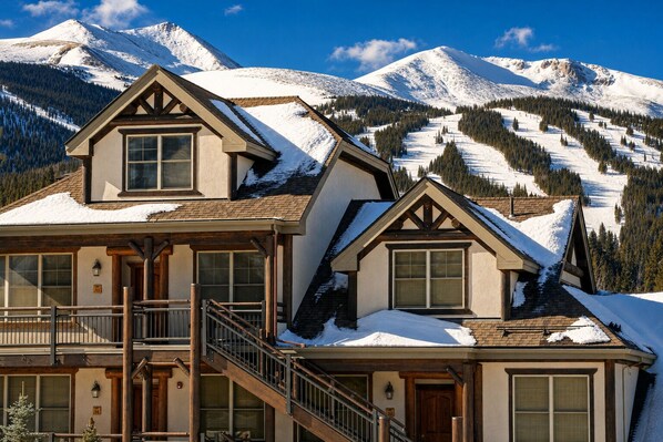 Un hôtel de style chalet doté d’un balcon, d’un escalier en bois et offrant une vue sur les montagnes.