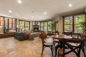 A spacious living room with a fireplace, comfortable seating, and large windows.