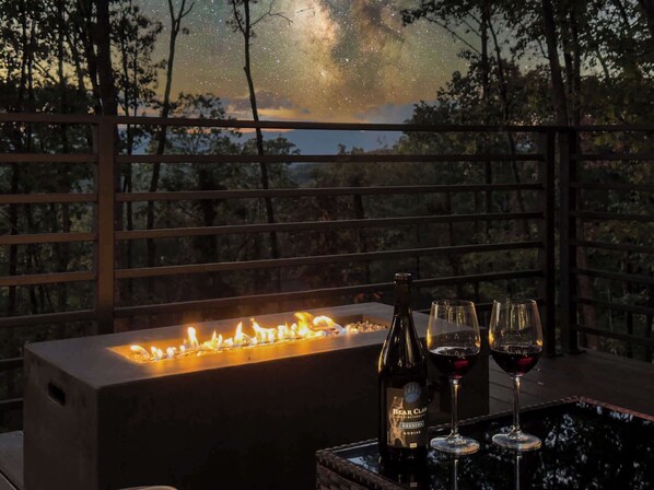 A fire feature, a bottle of Bear Claw wine, and two wine glasses on a table. - Luxury Mountain Lodge | Views, Hot Tub & Firepit (Blue Ridge)
