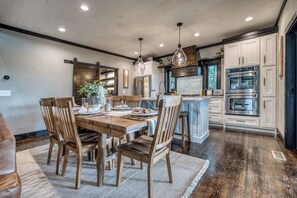 A dining area with a wooden table, chairs, and a vase of flowers. - Luxury Mountain Lodge | Views, Hot Tub & Firepit (Blue Ridge)