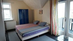 A bedroom with a bed, a wardrobe, a radiator, a window, and a balcony. - Relax in a Sunny Studio: Easy Stroll to Beach and Dune Views (Bergen aan Zee)