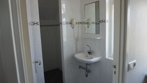 A bathroom with a white sink, a mirror, and a shower area. - Relax in a Sunny Studio: Easy Stroll to Beach and Dune Views (Bergen aan Zee)