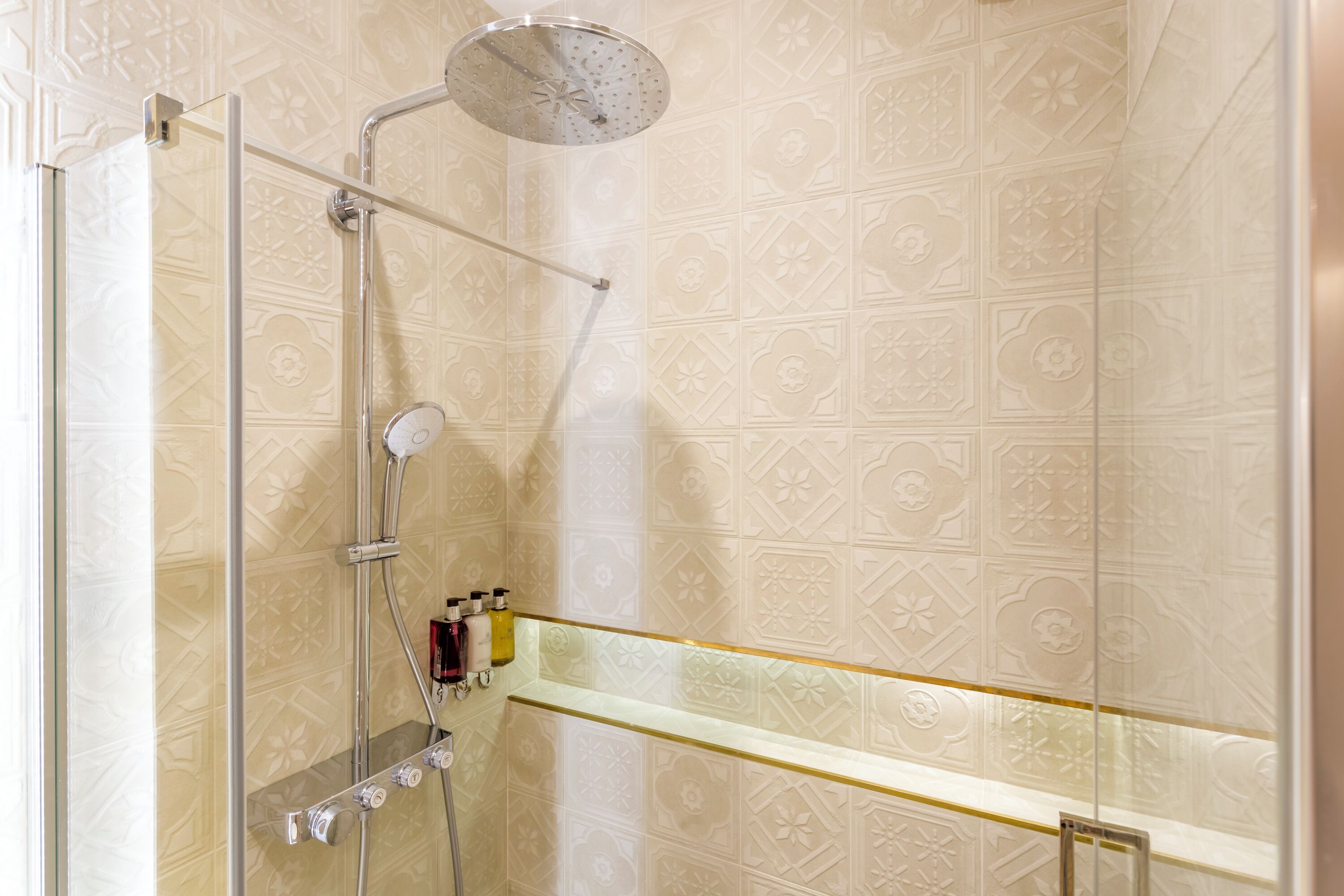 A shower with a glass door, a handheld showerhead, and a wall-mounted faucet.