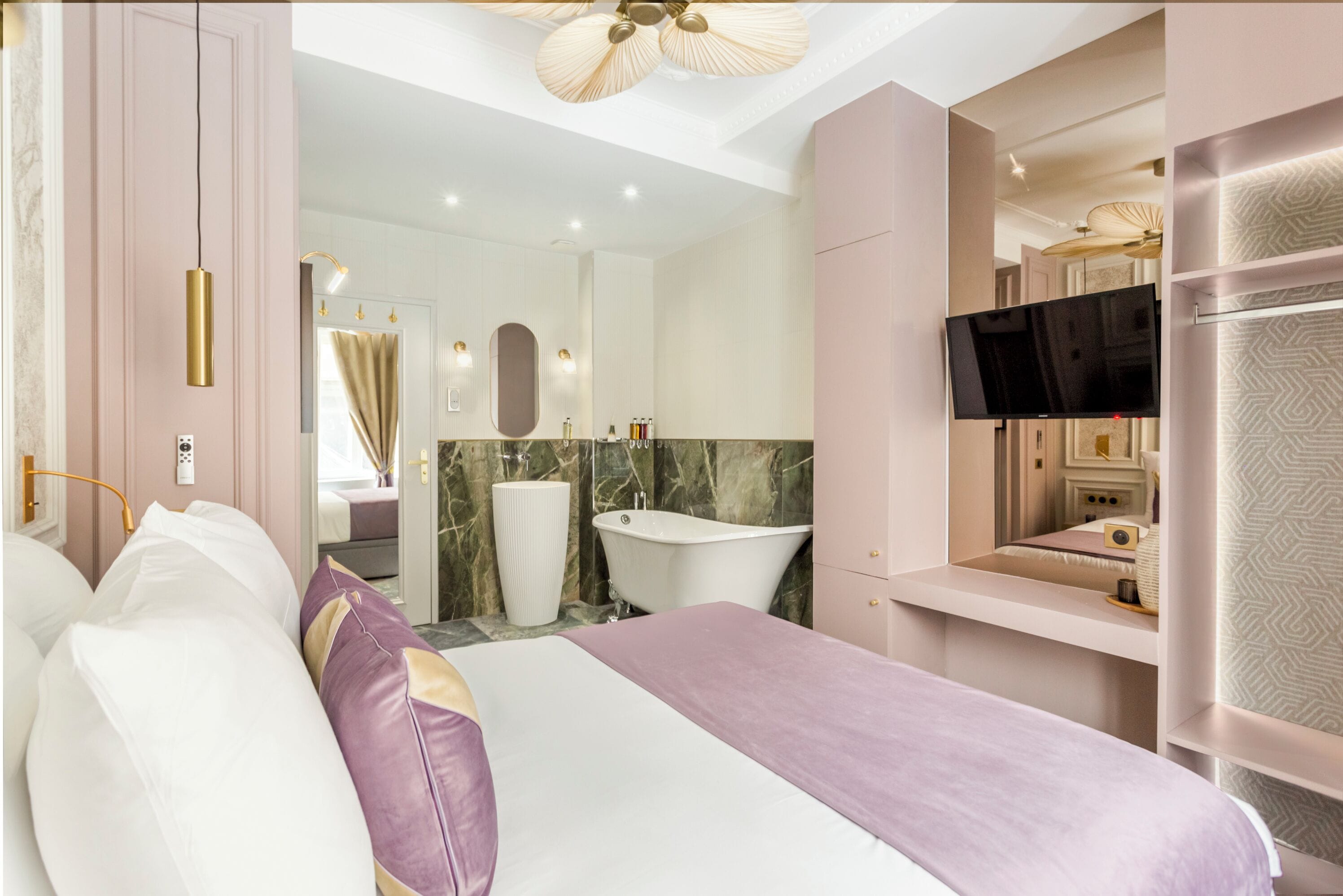 Un dormitorio moderno con una cama grande, un tocador con espejo, una televisión y una bañera.