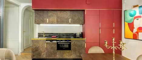 Eine moderne Küche mit Marmor-Schränken, einem eingebauten Backofen und einem Essbereich mit Holztisch und Stühlen.