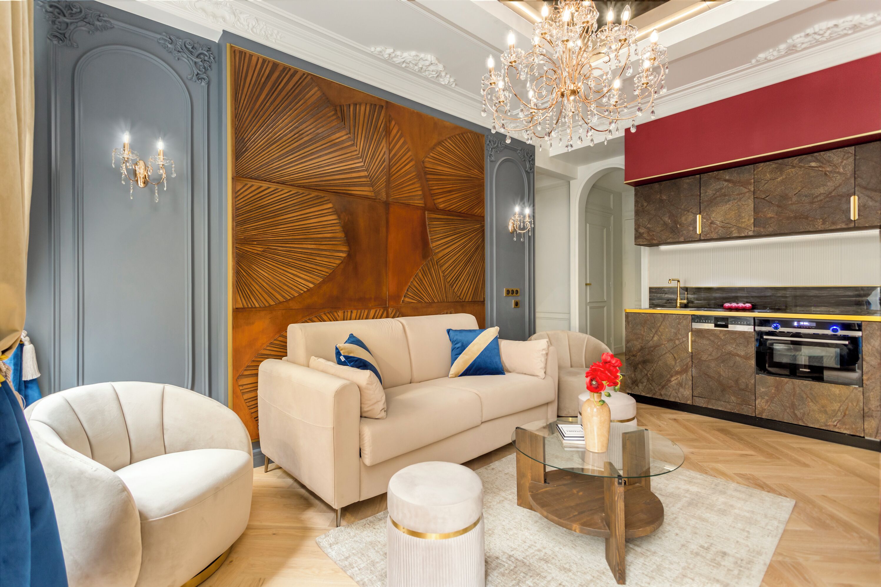 Un salon moderne avec un canapé beige, une table basse ronde en verre et un lustre.