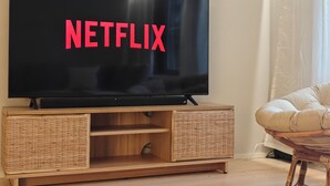 Een flatscreen televisie op een houten tv-meubel met gevlochten opbergvakken.
