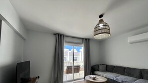 A modern living room with a flat-screen TV, a wooden coffee table, a sofa, and a large window with curtains. - 41 KAP - Stay Paradise Apartment (Paralimni)