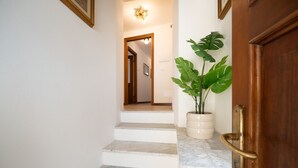 A staircase with marble steps leading to a room with a wooden door and a potted plant. - Mansarda Mella by Wonderful Italy (Bellagio)