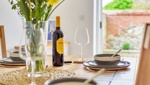 Una mesa de comedor dispuesta con platos, una botella de vino y una copa.
