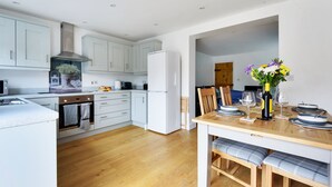 Una cocina moderna con gabinetes blancos, una campana de acero inoxidable y un horno empotrado.