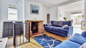 Una sala de estar con un sofá azul, una chimenea y un ventanal grande.
