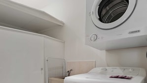 Een wasserette met een voorlader wasmachine en droger, een geventileerde droger, en een betegelde vloer.