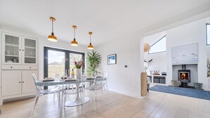 A modern kitchen with a dining area, wooden flooring, and pendant lighting.