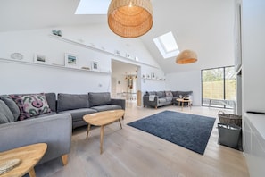 A spacious living area with a high ceiling, a large window, and a modern design.