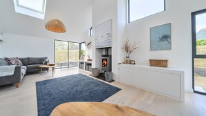 A modern living room with a fireplace, a sofa, a dining table, and a large window.