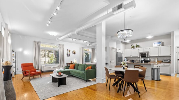 A spacious living area with a green sofa, a dining table, and a kitchen in the background. - Cozy Studio Near Plaza+Uptown (Charlotte)