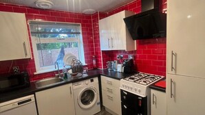 A compact kitchen with a washing machine, a gas stove, and a microwave.