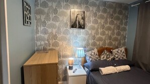 A bedroom with a bed, bedside tables, a lamp, a picture on the wall, and a patterned rug.