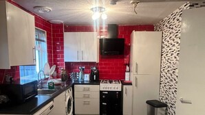 A compact kitchen with a washing machine, a stove, and a microwave.