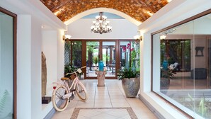 A spacious hallway with a tiled floor, a pink bicycle, and a large potted plant.