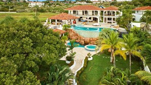 A resort with a large pool, palm trees, and a view of the surrounding landscape.