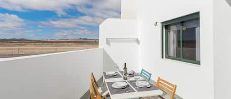 Una mesa de comedor con platos, vasos y cubiertos en una terraza con vistas al paisaje desértico.