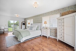 Un dormitorio con cama, mesitas de noche, cómoda y balcón.