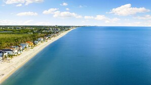 A coastal area with a long beach, beachfront properties, and a clear blue sky. - Manatee Bay - Waterfront Pool Home & Walk to Bonita Beach (Bonita Springs)