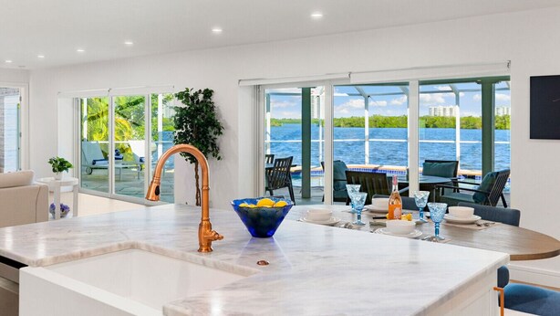 A modern kitchen with a large island, a copper faucet, and a bowl of lemons. - Manatee Bay - Waterfront Pool Home & Walk to Bonita Beach (Bonita Springs)