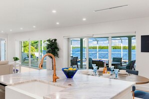 A modern kitchen with a large island, a copper faucet, and a bowl of lemons.