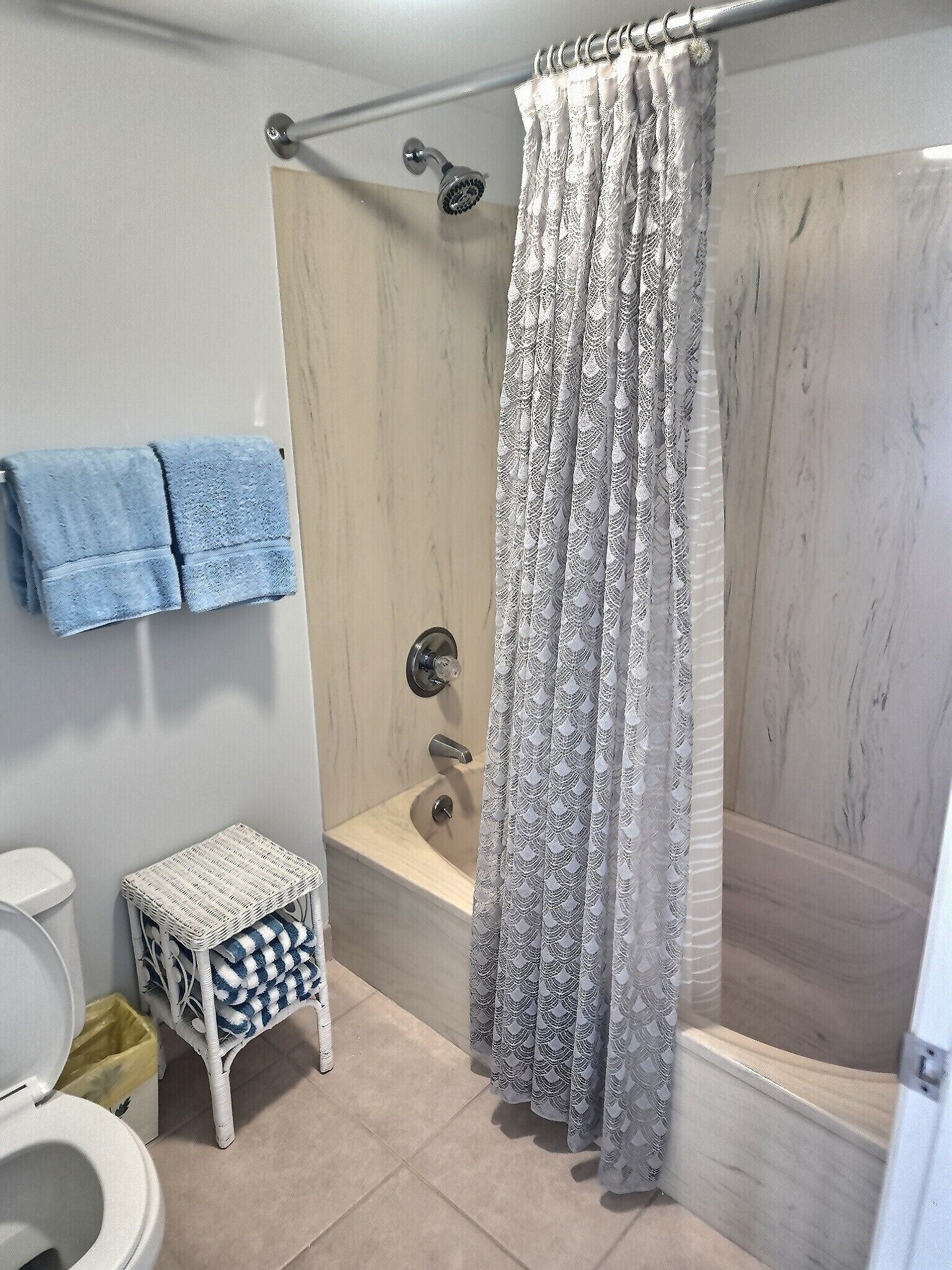 Ein Badezimmer mit Dusche, Toilette und einem kleinen Tisch mit einem Korb.
