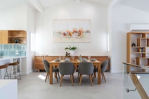 A modern dining area with a wooden table, grey chairs, and a glass railing.